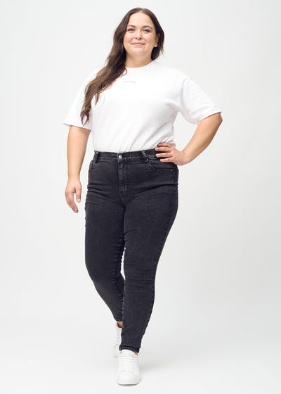 Fuldt billede af en plus-size model i mørkegrå denim skinny jeans.